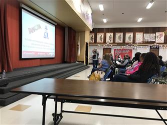 A presentation on a screen in a multipurpose room
