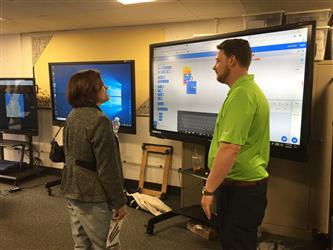 A man and a woman speaking with each other in front of screens