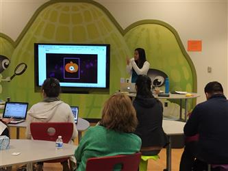 A presentation being given by a woman with a large TV screen