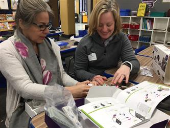 Two teachers reviewing material in a book