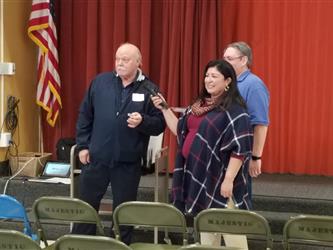 A woman holding a microphone up for a man so he can speak